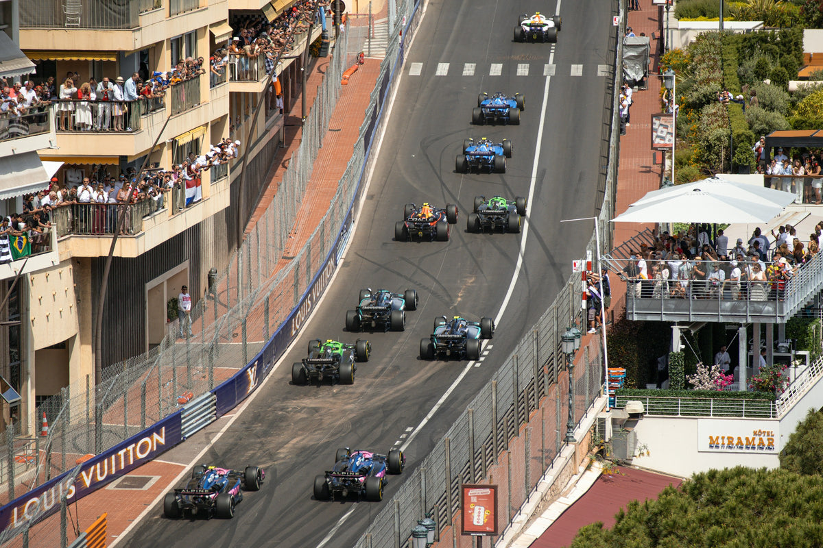 Formula 1 cars climbing past crowded terraces at the start of a Grand Prix
